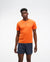 hoka everyrun short sleeve running t-shirt for men, bright orange colour with silver reflective HOKA logo, full body profile of a man wearing hoka tee with grey shorts on a white background