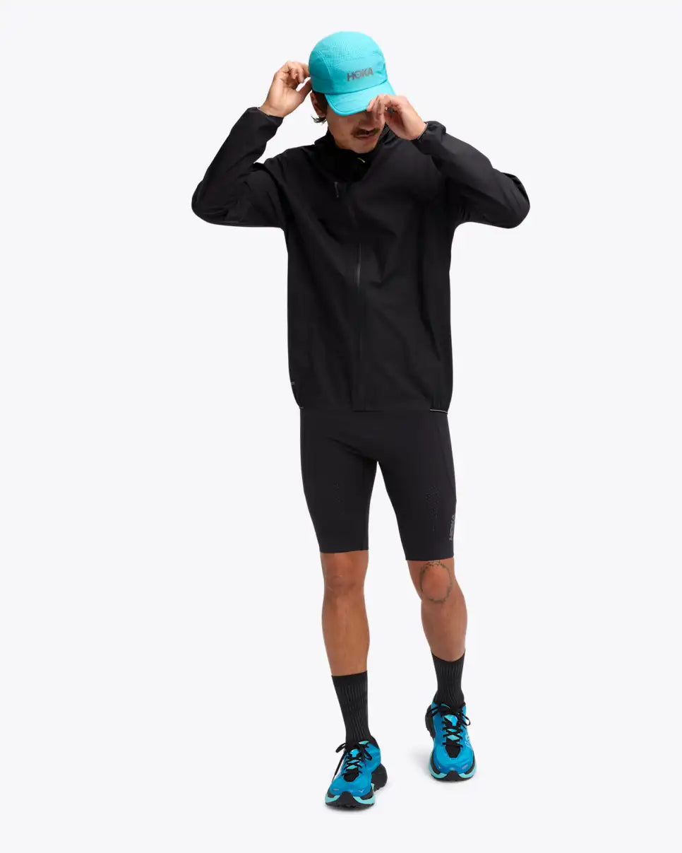 man wearing hoka skybreeze waterproof jacket, light waterproof gtx jacket for running, black colour with reflective details, full body view