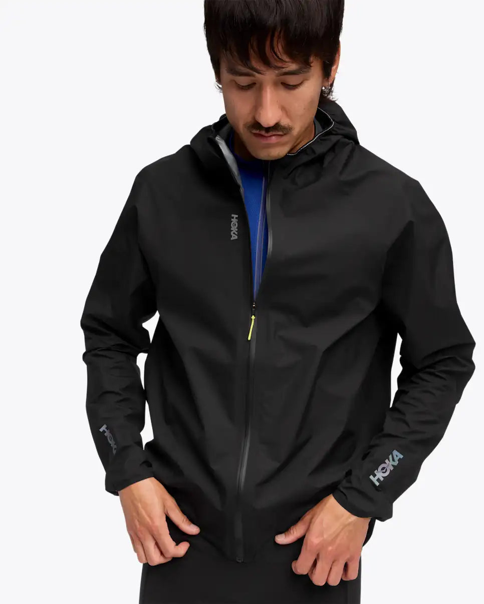close up of man wearing hoka skybreeze waterproof jacket, light waterproof gtx jacket for running, black colour with reflective details