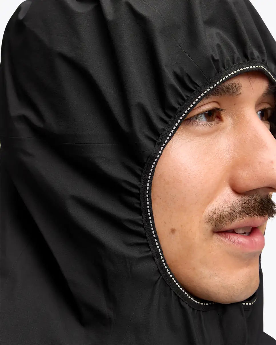 man wearing hoka skybreeze waterproof jacket, light waterproof gtx jacket for running, black colour with reflective details,  view of hood