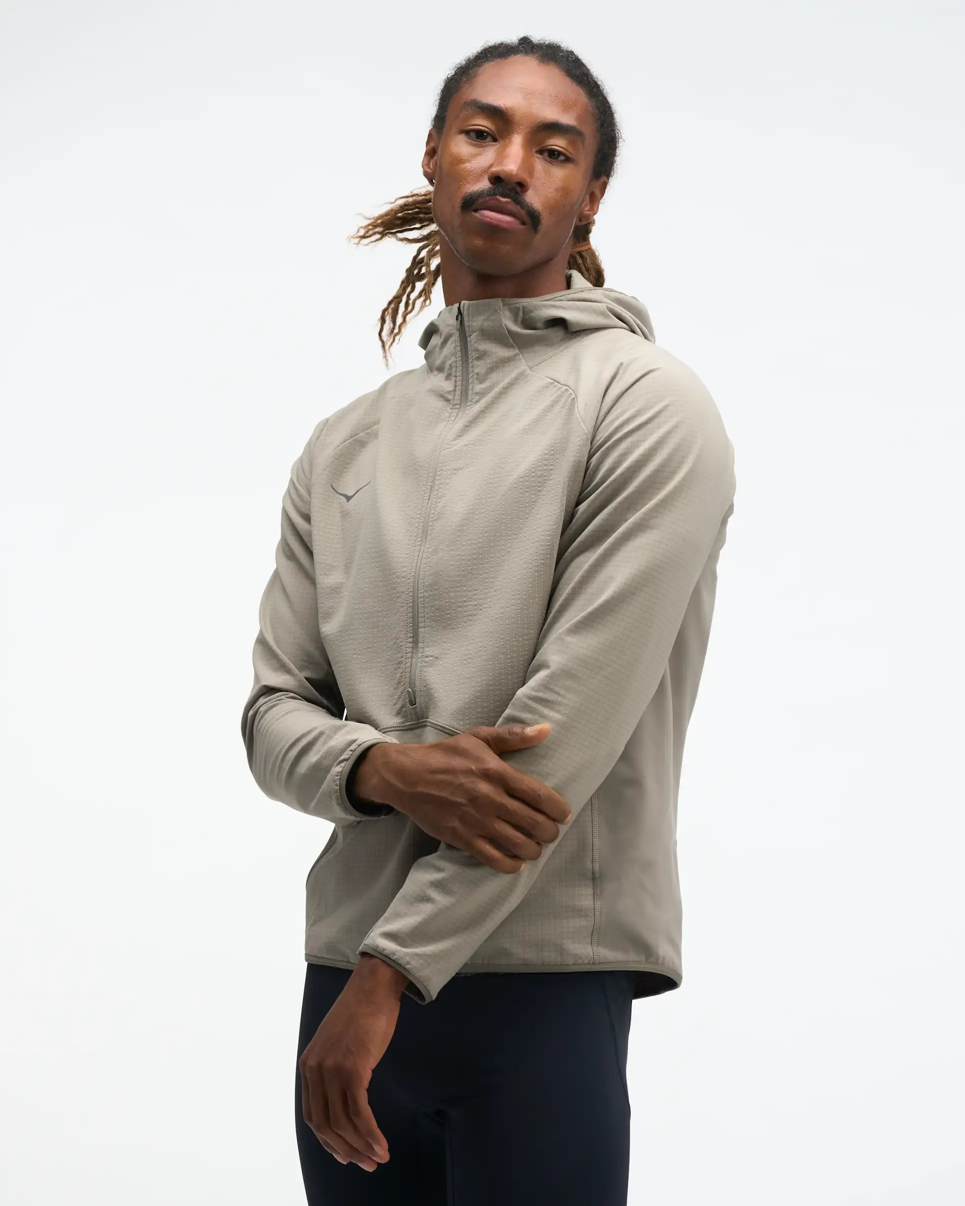 hoka men's skyglow half zip running top,  water resistant, stretchy long-sleeve pull over with a hood, light grey colour, front view of model wearing half-zip with black trousers on a white background
