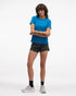 hoka everyrun short sleeve running t-shirt for women, blue colour with silver reflective logo, woman wearing hoka tee with black shorts on a white background
