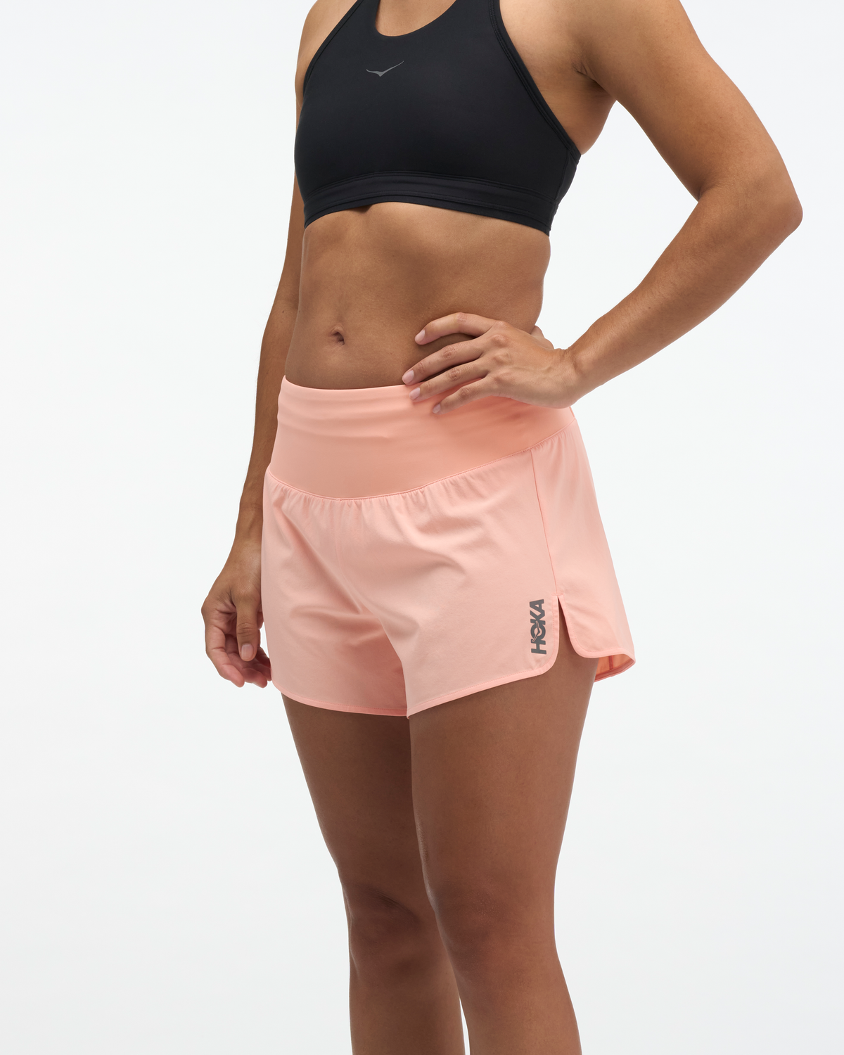hoka womens glide short mr 3.5 brief, lightweight running short, solid peach colour, woman wearing short with black sports bra on white background