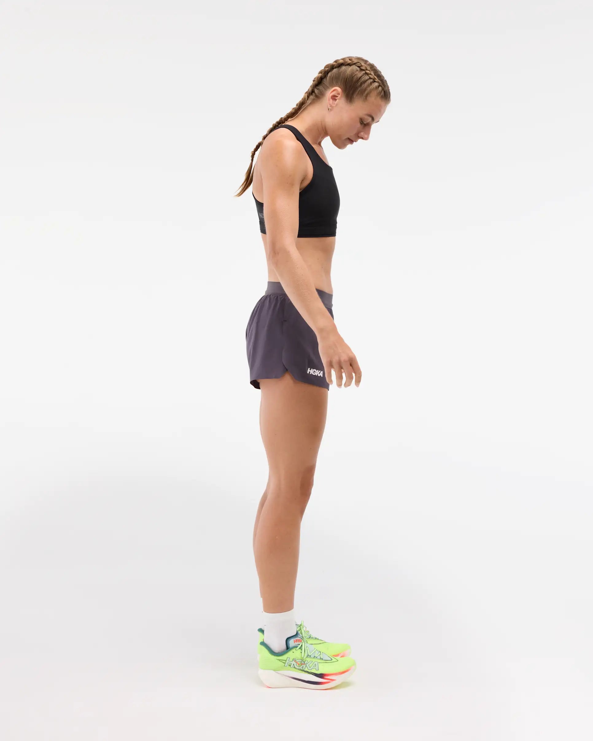 Womens Hoka race day split short in the squid ink colourway. Side view of woman wearing dark grey hoka shorts