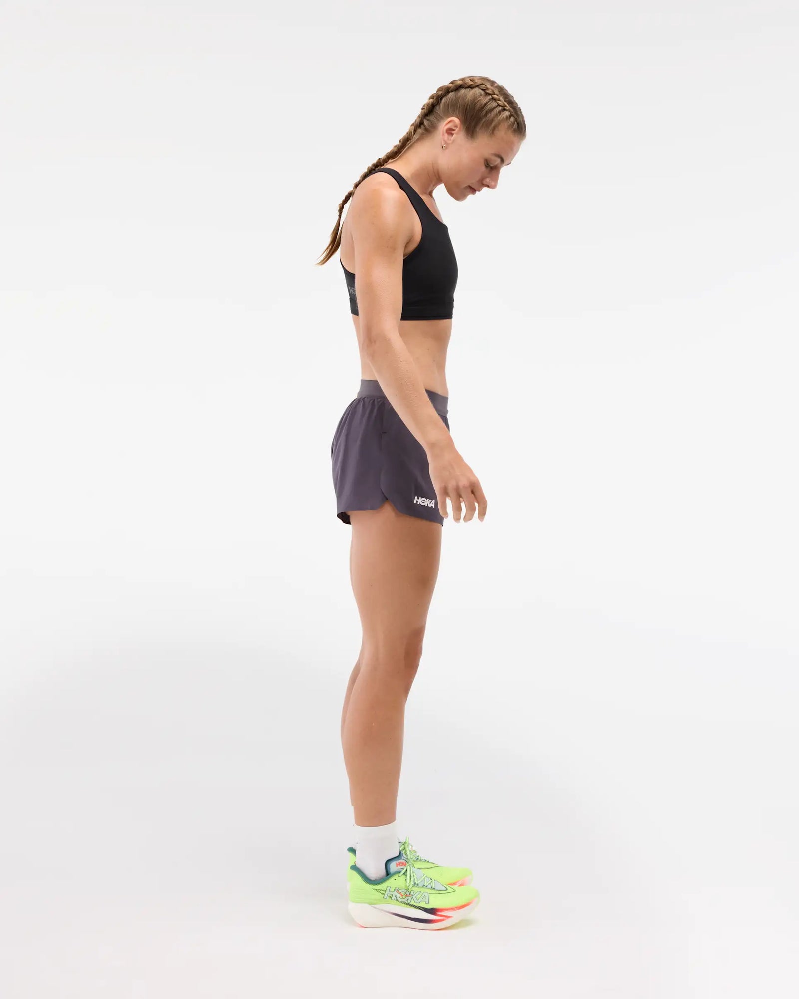 Womens Hoka race day split short in the squid ink colourway. Side view of woman wearing dark grey hoka shorts