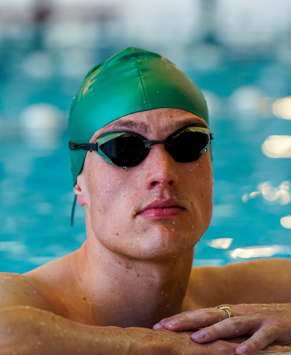man wearing a green swim cap with the sage green huub eternal swim goggles in pool close up of face