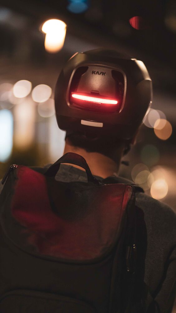 Person wearing a kask moebius helmet with an integrated red light at night