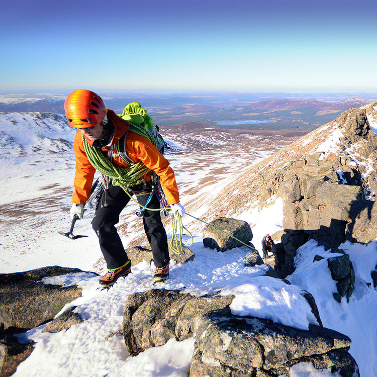 Person climbing a snowy mountain with a scenic view background wearing lifesystem sun cream 