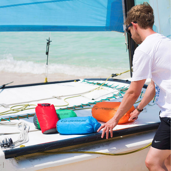 image of a man next to an assortment of lifeventure ultralight dry bags being used on a boat