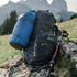 lifeventure ultralight dry bag, 5 litre capacity, waterproof and durable storage bag, bright blue colour, shown paired with a black rucksack on a countryside trail path