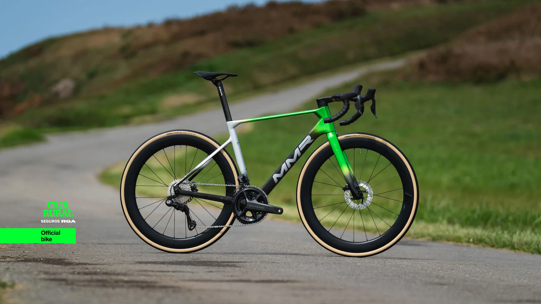 pic of an mmr aelion road bike on a road scene with text saying official bike of the caja rural seguros rga