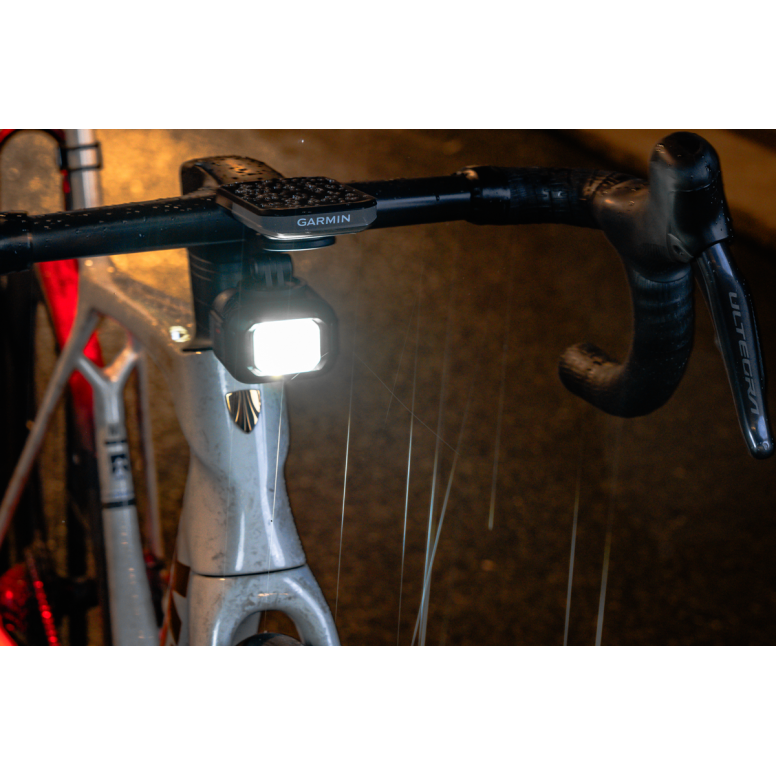 moon titan max bike light, small square bike ligt under front handlebars of bike, light turned on in dark rain