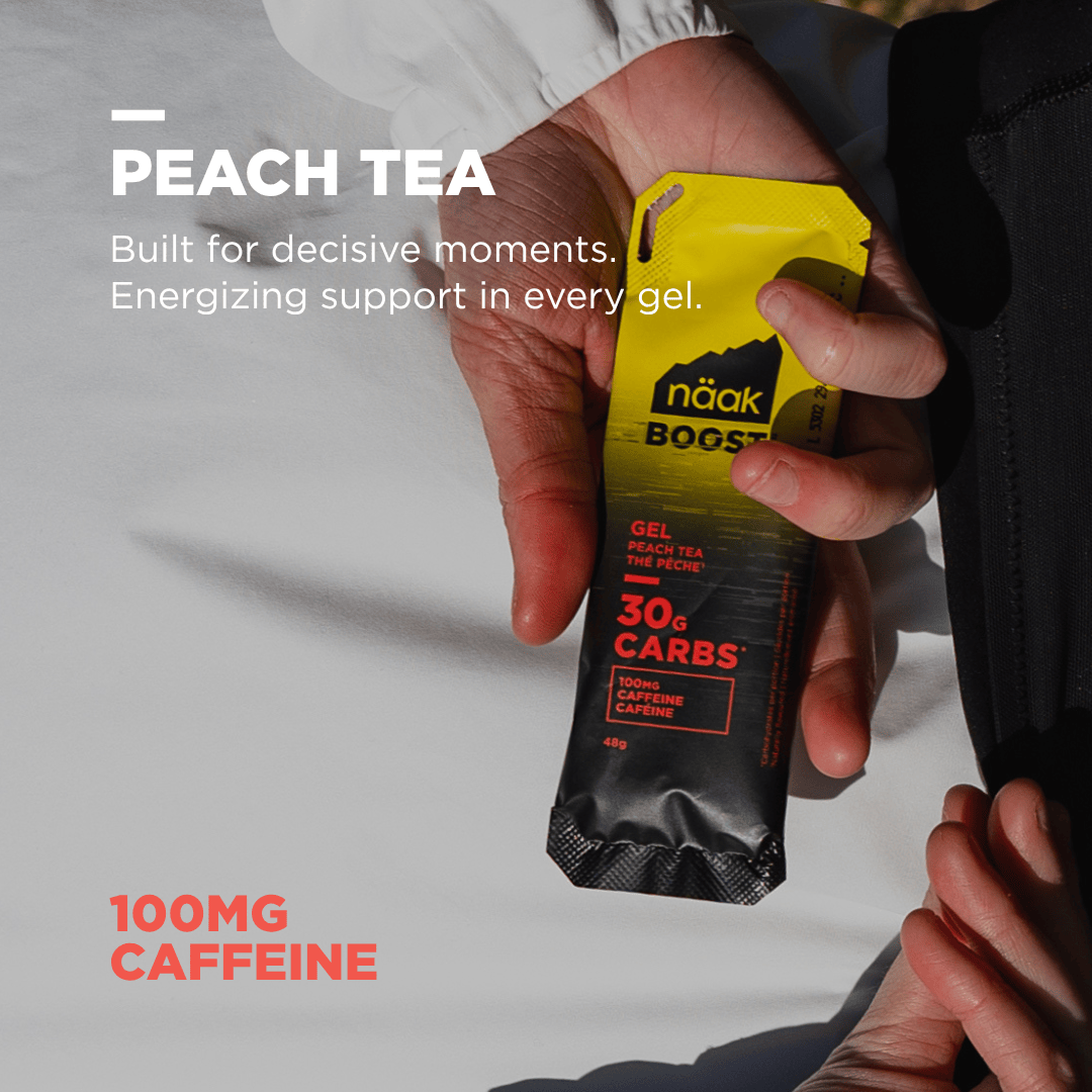 person's hand holding naak boost energy gel, peach tea flavour with added caffeine