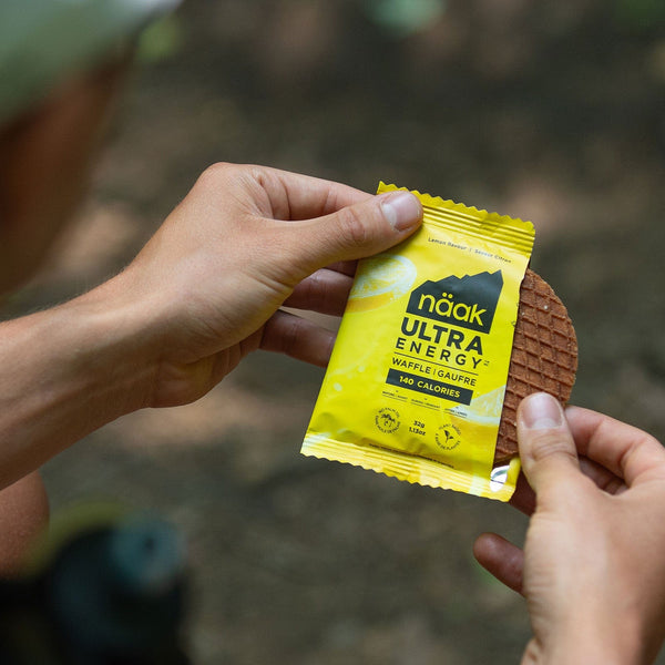 naak ultra energy waffle, running and cycling carb and protein nutrition, lemon flavoured waffle, open package with hands holding waffle