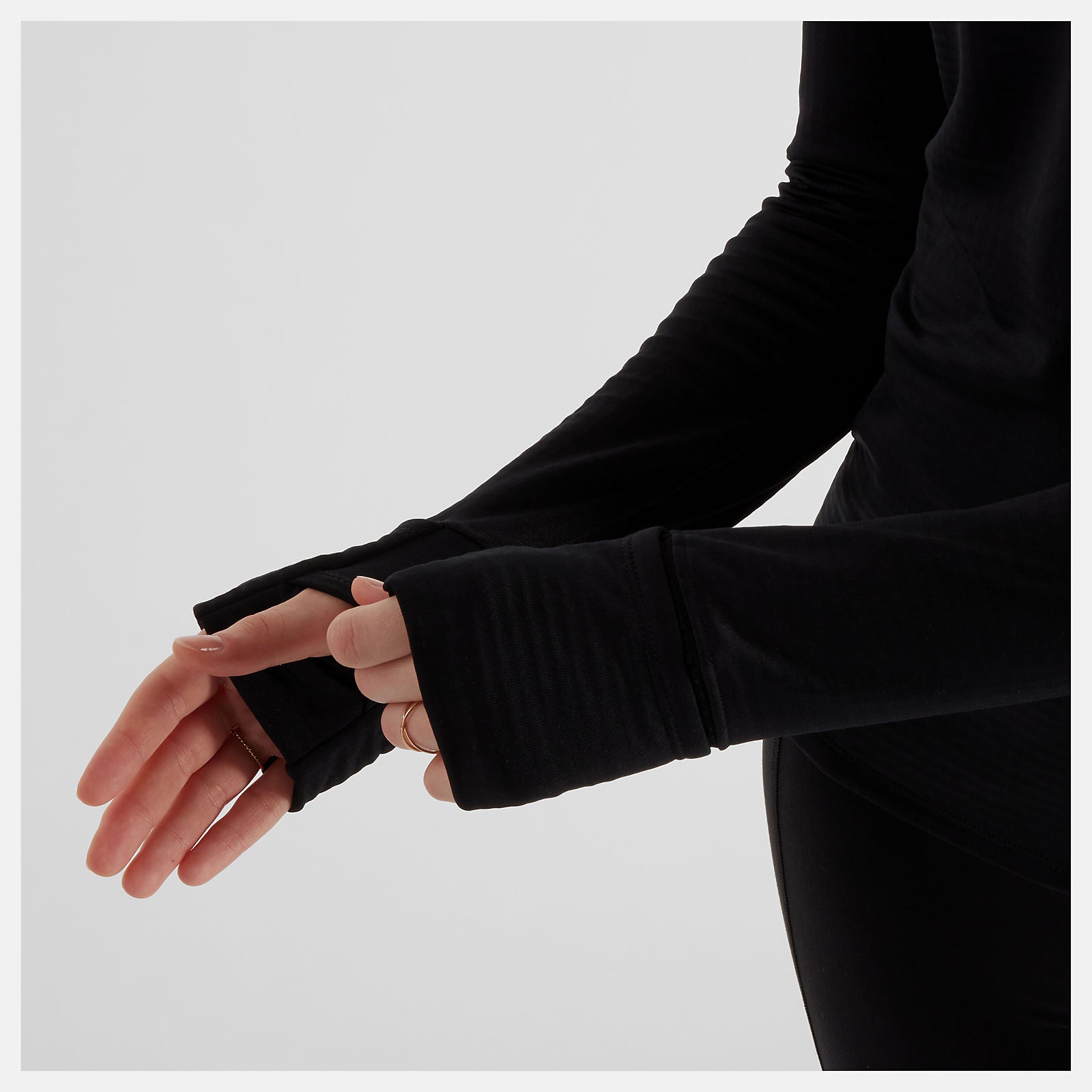 Woman wearing NB long sleeve run top, showing thumb hole in sleeve to keep hands warm when running
