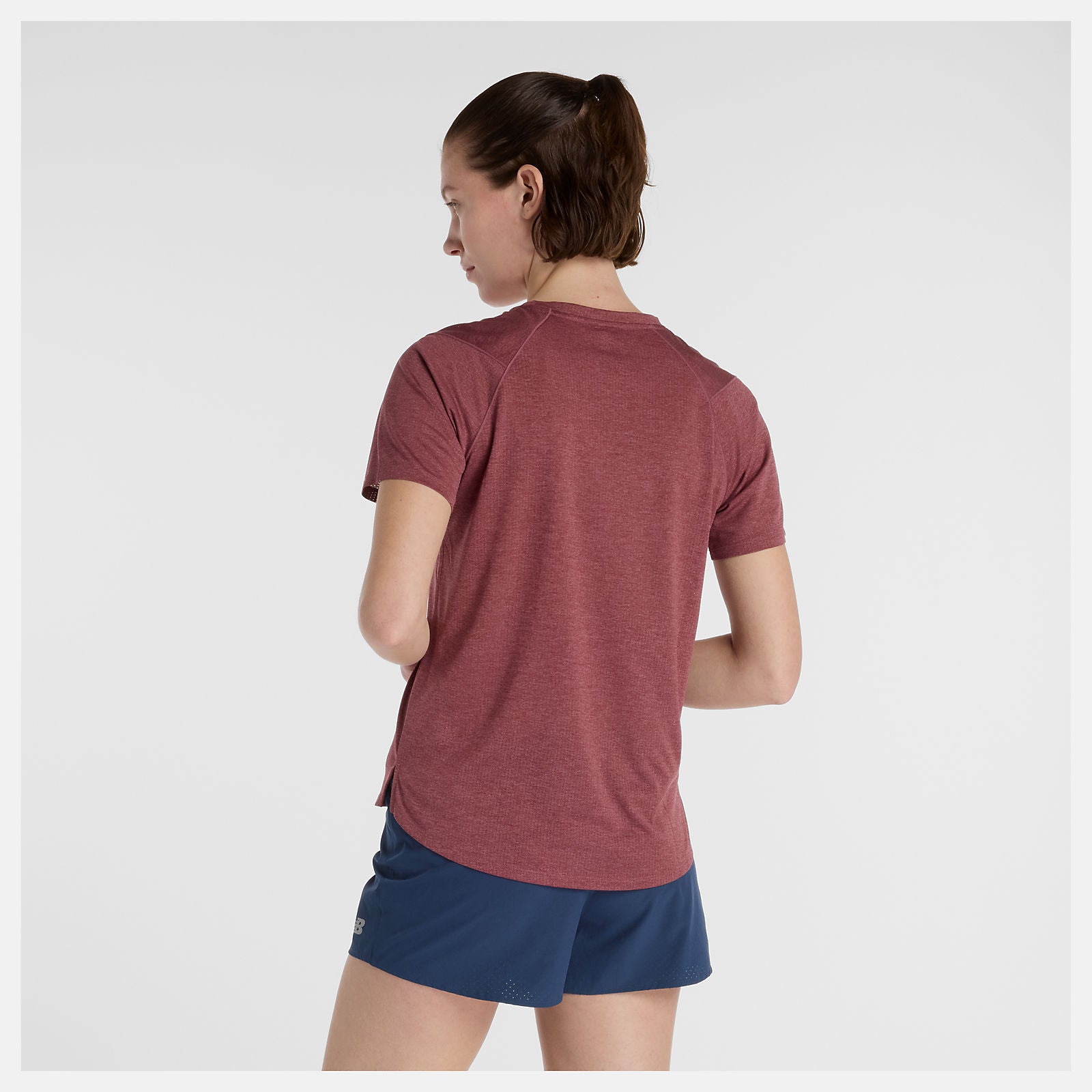 woman wearing nb athletics run tee in washed burgundy colour, showing back