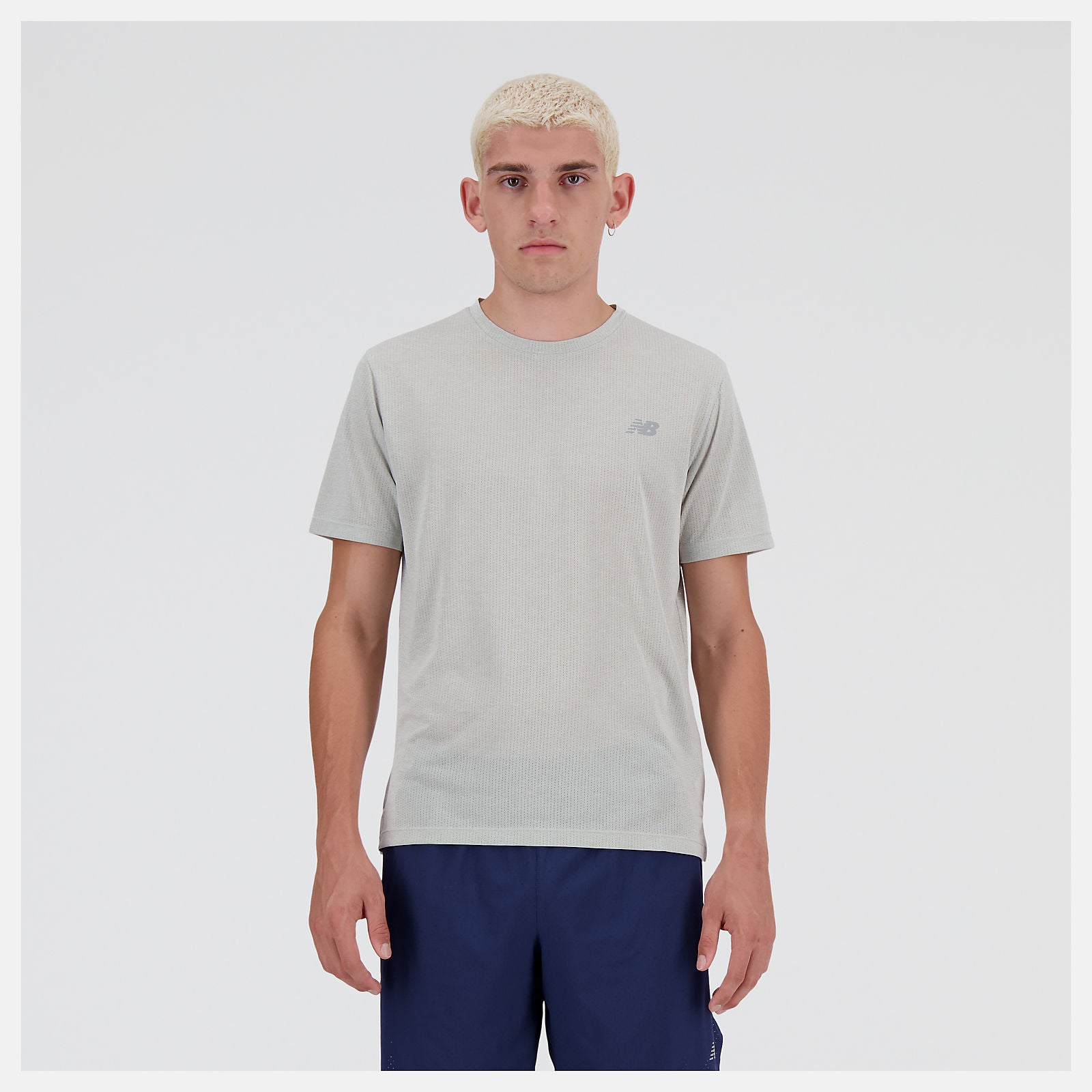 Man wearing a new balance gray run t-shirt and navy shorts on a white background