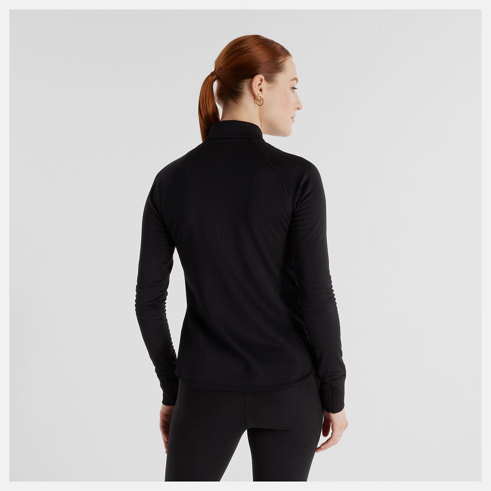Woman wearing a new balance black long-sleeve athletic top 