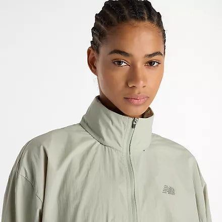 new balance athletics packable jacket for women, light wind breaker jacket that packs away into built in bag, light green colour, woman wearing nb jacket close up of neckline zipped up