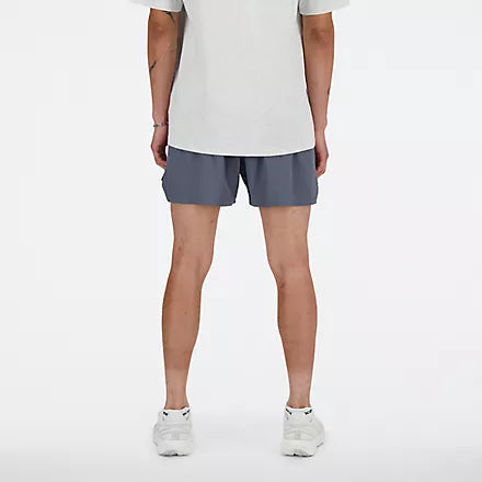 new balance rc short for men, lightweight 5in length running short for men, grey colour, male model chest down wearing grey nb shorts and white shirt with white shoes back