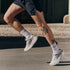 nb supercomp rebel mens, lightweight speed training and racing shoe, white and cream with black and red details, close up of mans legs running in shoes on concrete