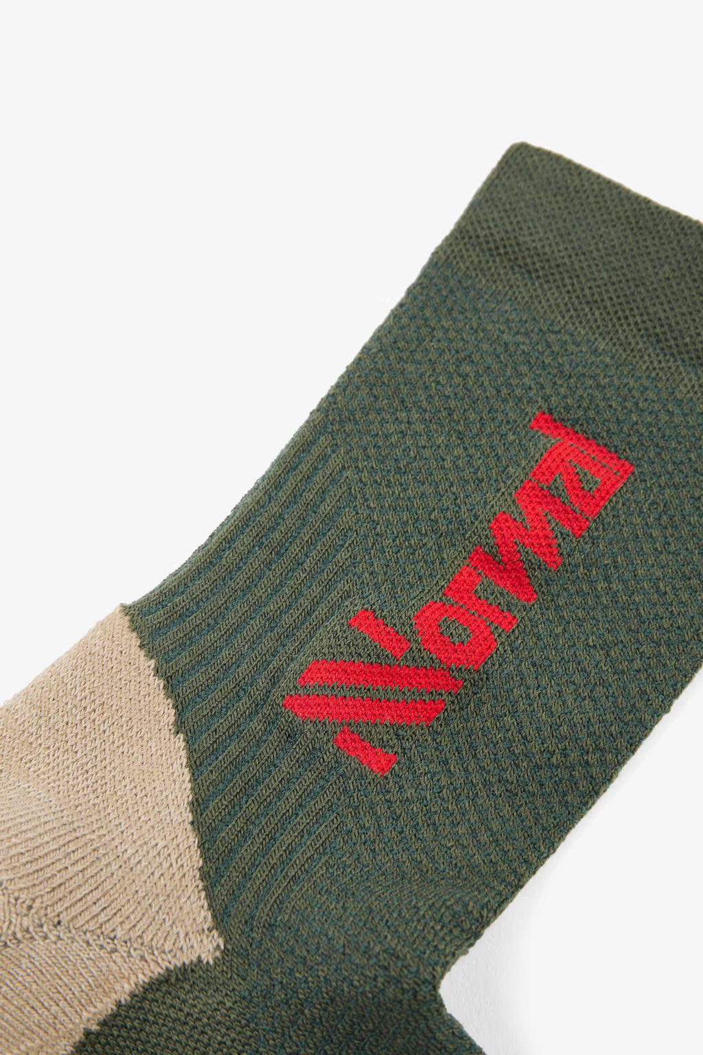 nnormal merino sock for trail running with slight compression and great thermoregulation, dark green colour with tan heels and red logo, close up of ankle sock material