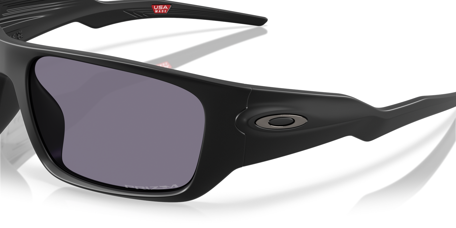 Oakley masseter sunglasses with black frame and grey prizm lenses, closeup of one lens and logo