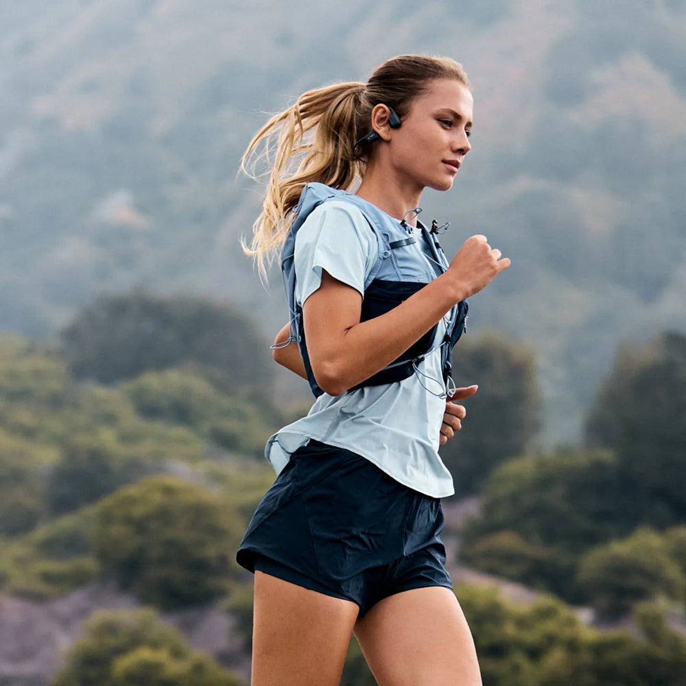 woman running with shokz open runpro bone conduction headphones on her head