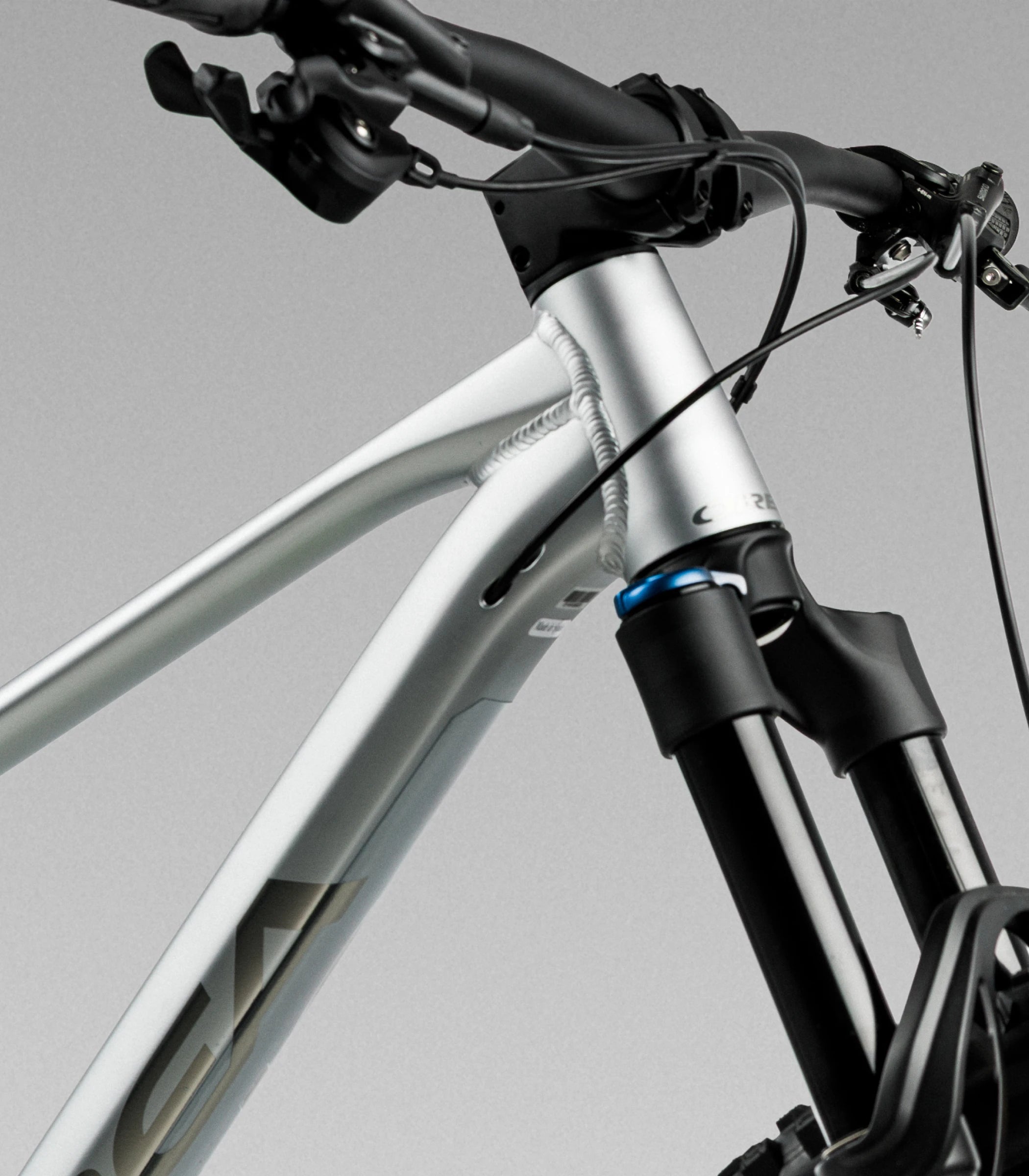Close-up of a silver orbea laufey mountain bike frame and front fork, matte silver frame, black handlebars, and black suspension fork 