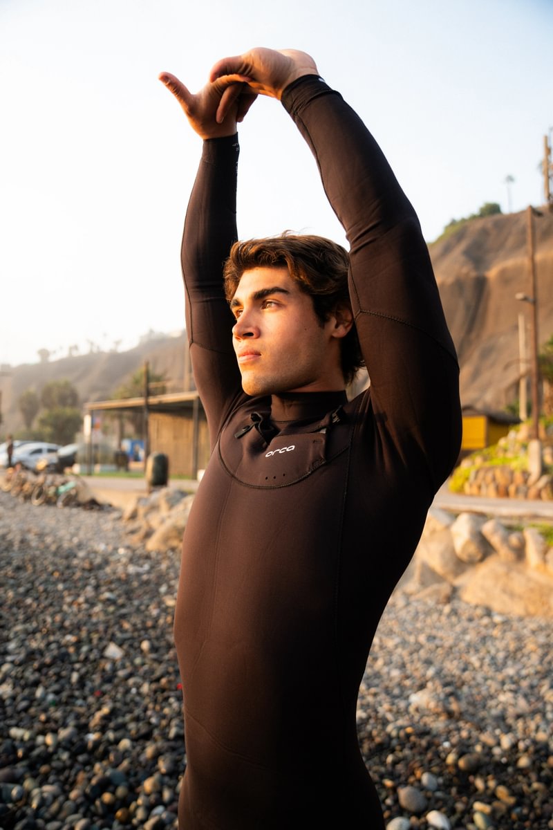 Man stretching in Orca Tango 5:4 surfing wetsuit for men, flexible surf wetsuit