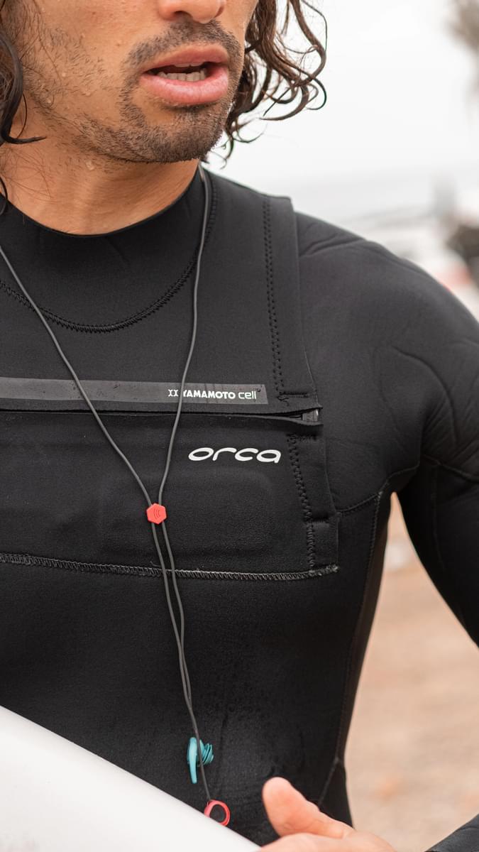 Close up of front of Orca Tango 5:4 surfing wetsuit on a man, also wearing surf ears