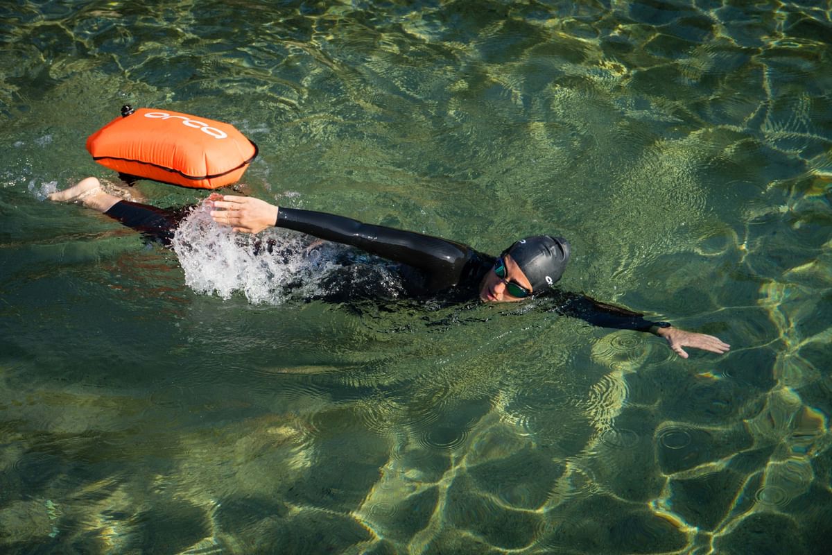 man swimming in the sea wearing an orca wetsuit and an Orca tow float for safety