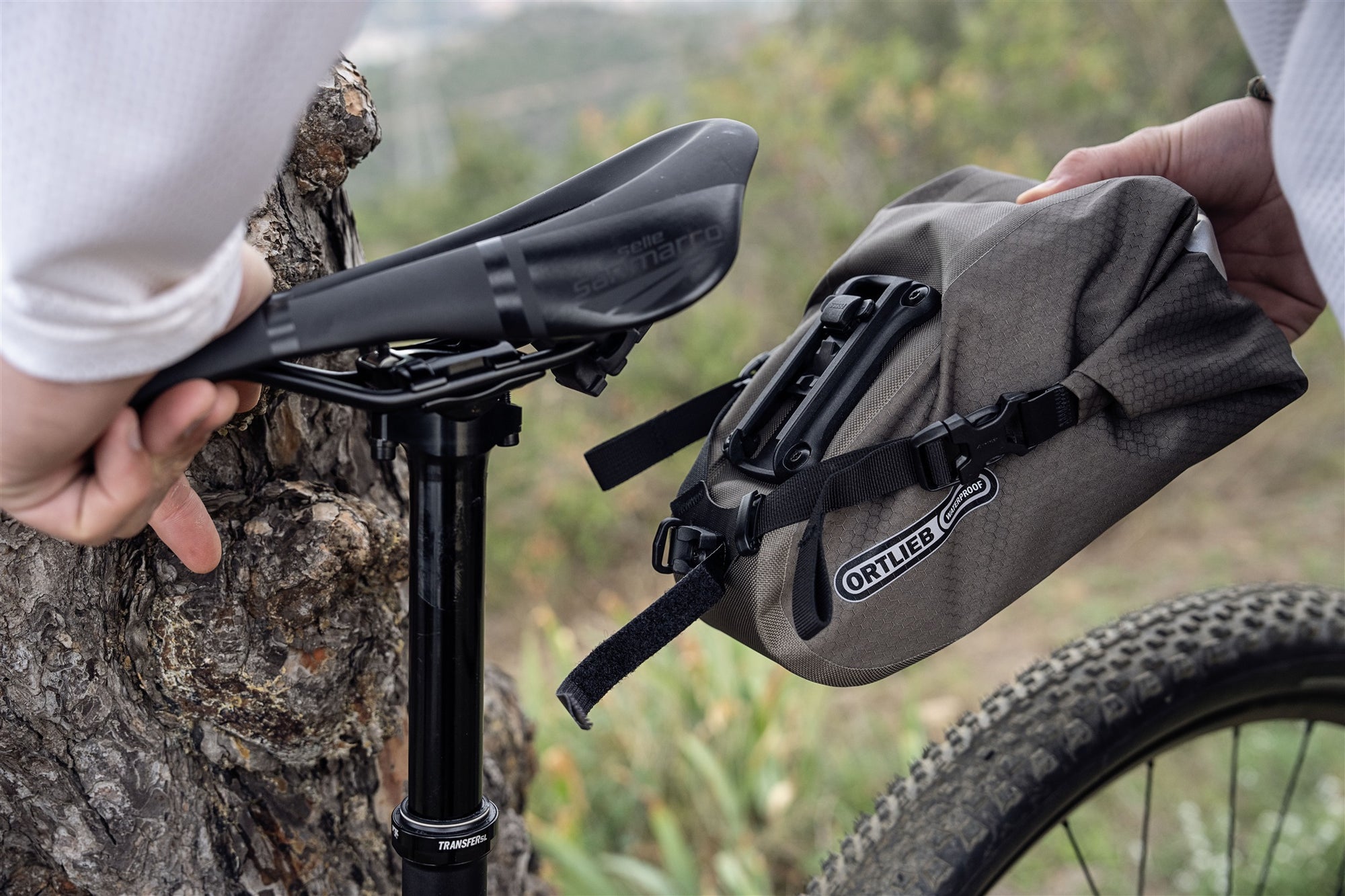 Ortlieb bicycle saddle bag being attached to a bike with a natural outdoor background