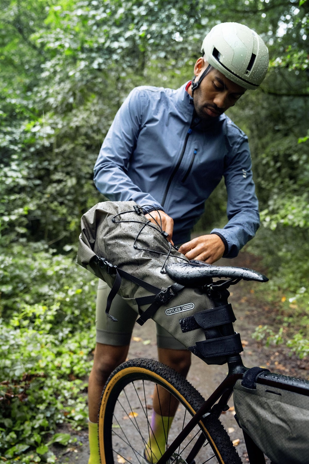 Person preparing a bike with a ortlieb seat bag in a forest setting
