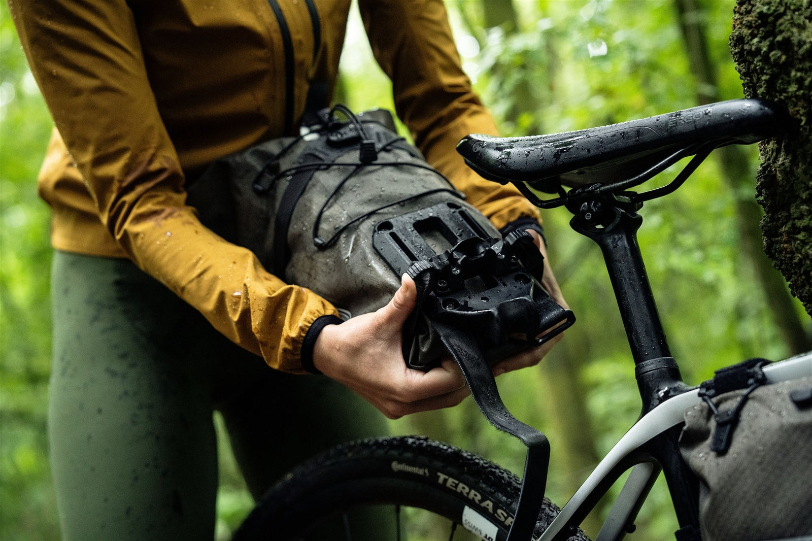 Person adjusting an orlieb bike bag on a bicycle in a forest setting