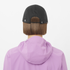 salomon bonatti pro cap with five panels, waterproof cap for running, black colour with a white logo, back view model wearing salomon cap with pink salomon jacket 