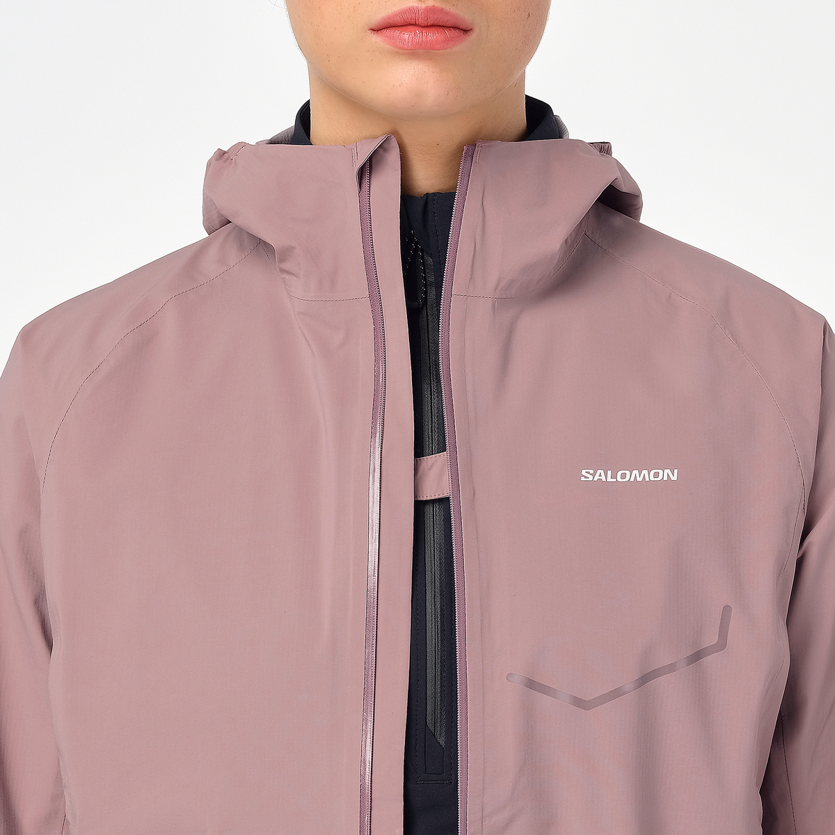 Woman wearing the salomon bonatti waterproof jacket, in antler colour, close up of button feature on chest to prevent jacket opening in the wind
