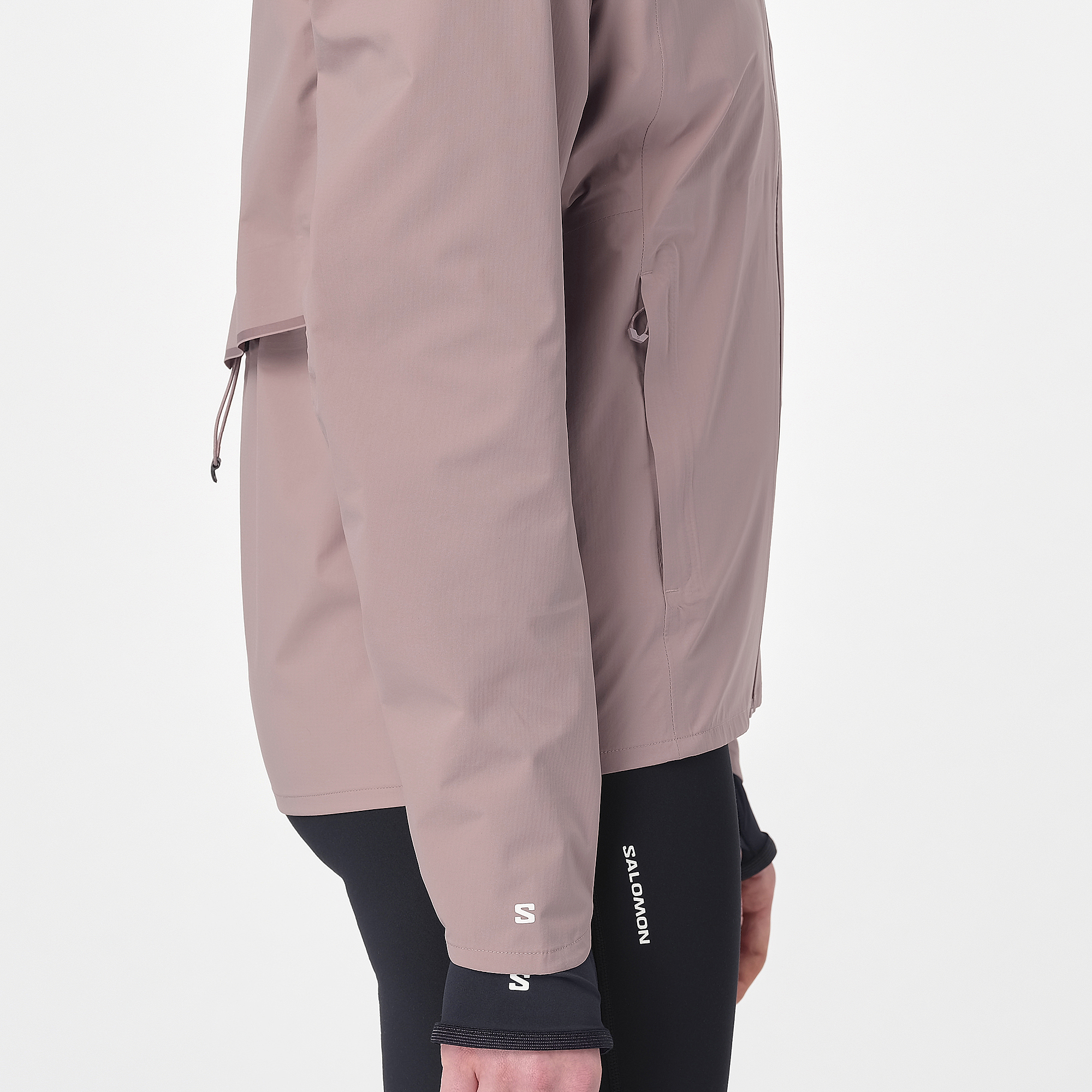Woman wearing the salomon bonatti waterproof jacket, in antler colour, side view of zip pocket, reflective logo on sleeve