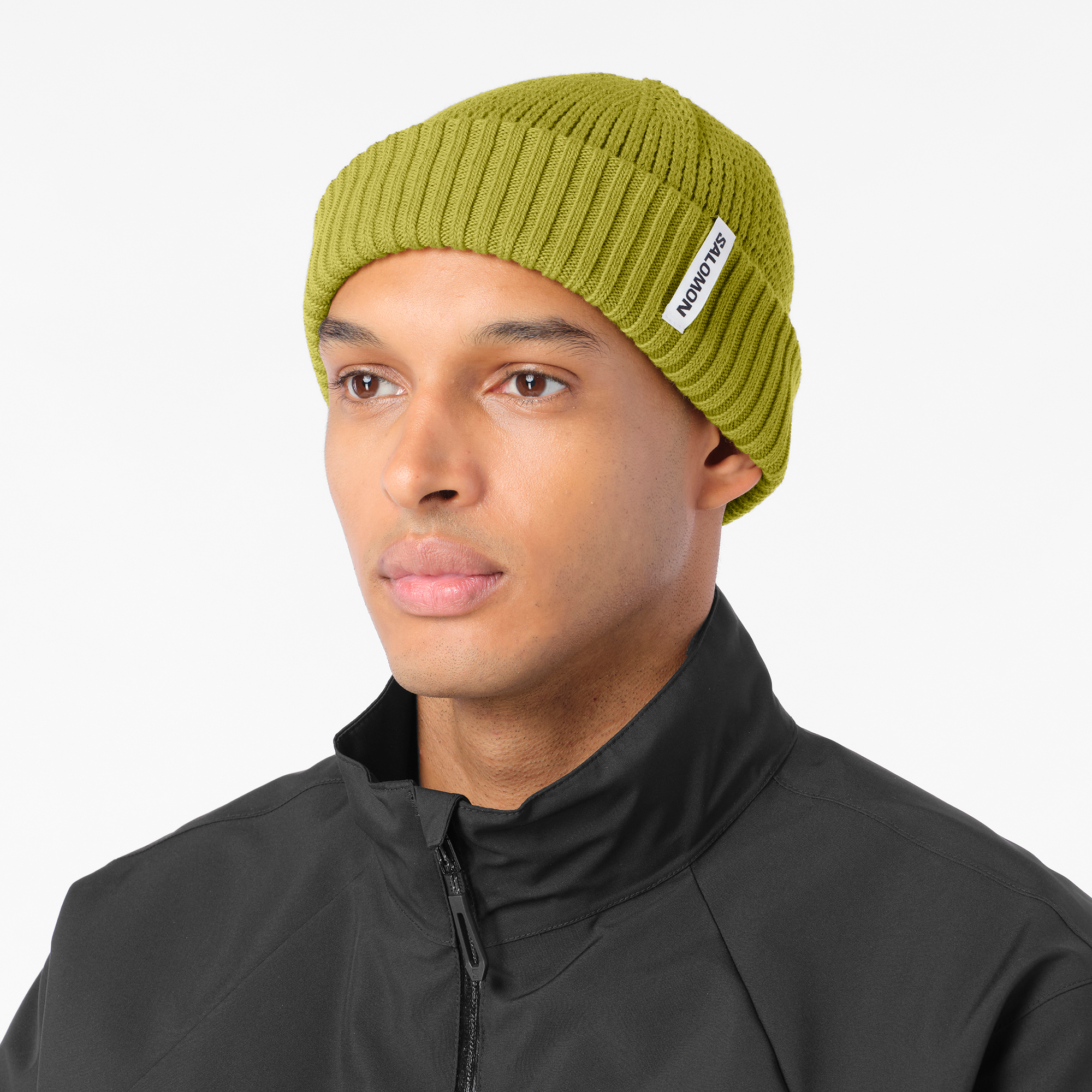 salomon docker beanie, wool blend hat for warmth and comfort, olive green colour, man wearing salomon beanie with black jacket on a white background