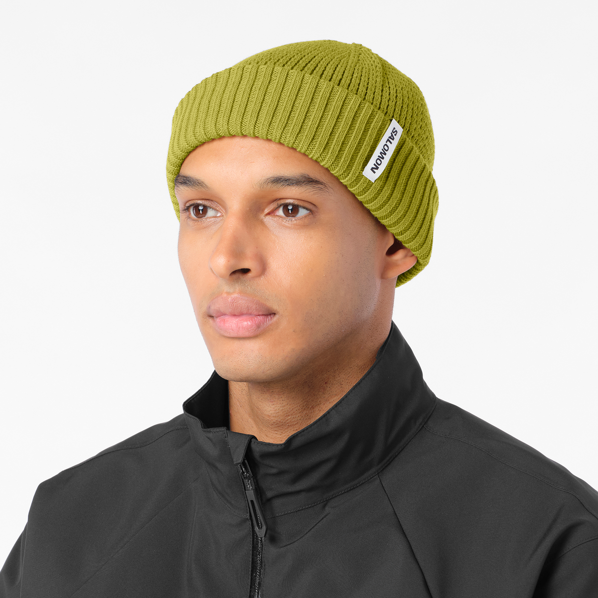 salomon docker beanie, wool blend hat for warmth and comfort, olive green colour, man wearing salomon beanie with black jacket on a white background