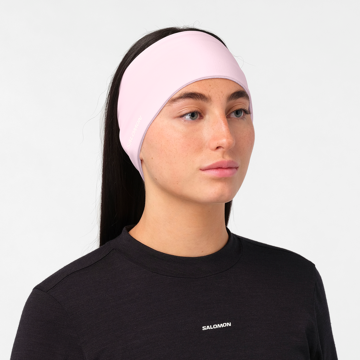salomon run tech headband for all gender, warm and water repellent head accessory for running, light pink colour with reflective salomon logo, close up of woman wearing salomon headband with a black top on a white background