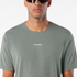 salomon shakeout core short sleeve t-shirt for men, lightweight run tee, grey colour with reflective salomon logo, close up of man wearing salomon tee on a white background 