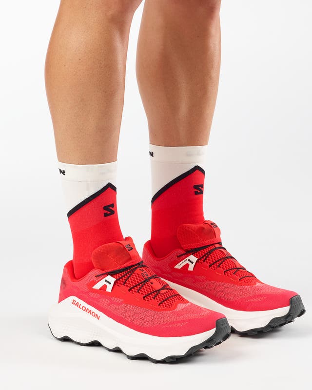 mens salomon ultra glide 4, mens trail shoe in the fiery red, vanilla ice, black colourway. picture of the shoes being worn by a model with a white background