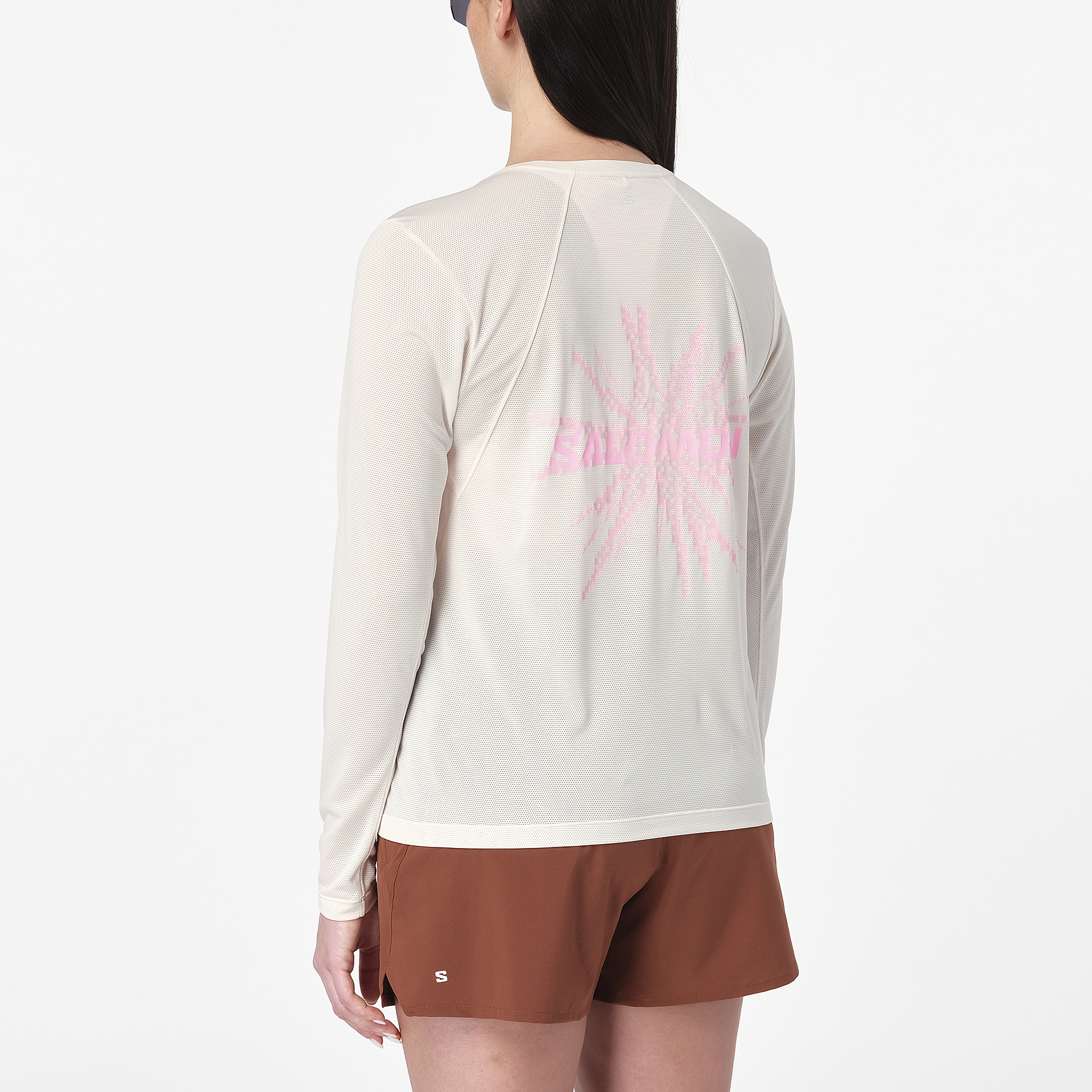 salomon womens shakeout core long sleeve, super breathable long sleeve shirt, white with light pink design, back of woman wearing shirt with pink logo