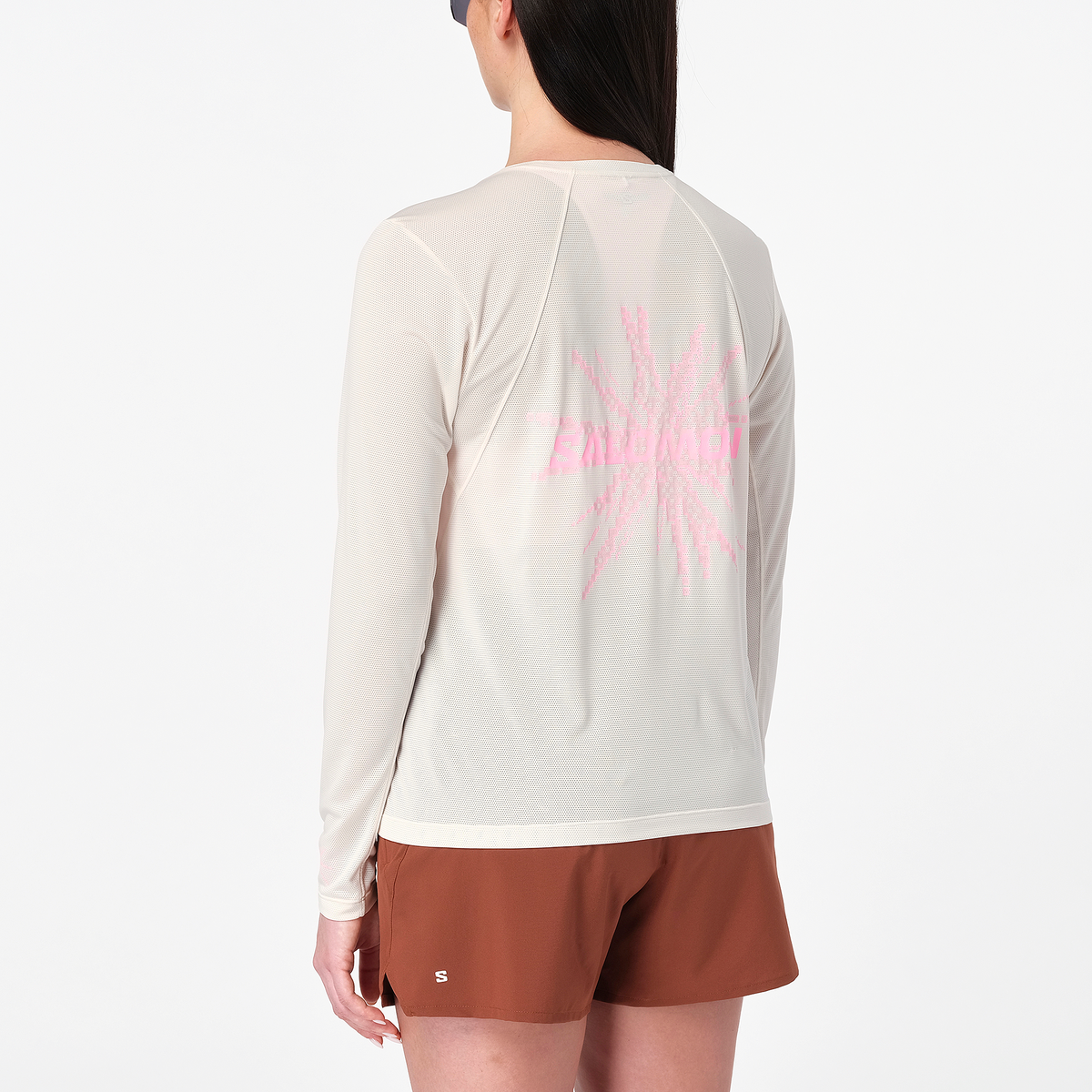 salomon womens shakeout core long sleeve, super breathable long sleeve shirt, white with light pink design, back of woman wearing shirt with pink logo