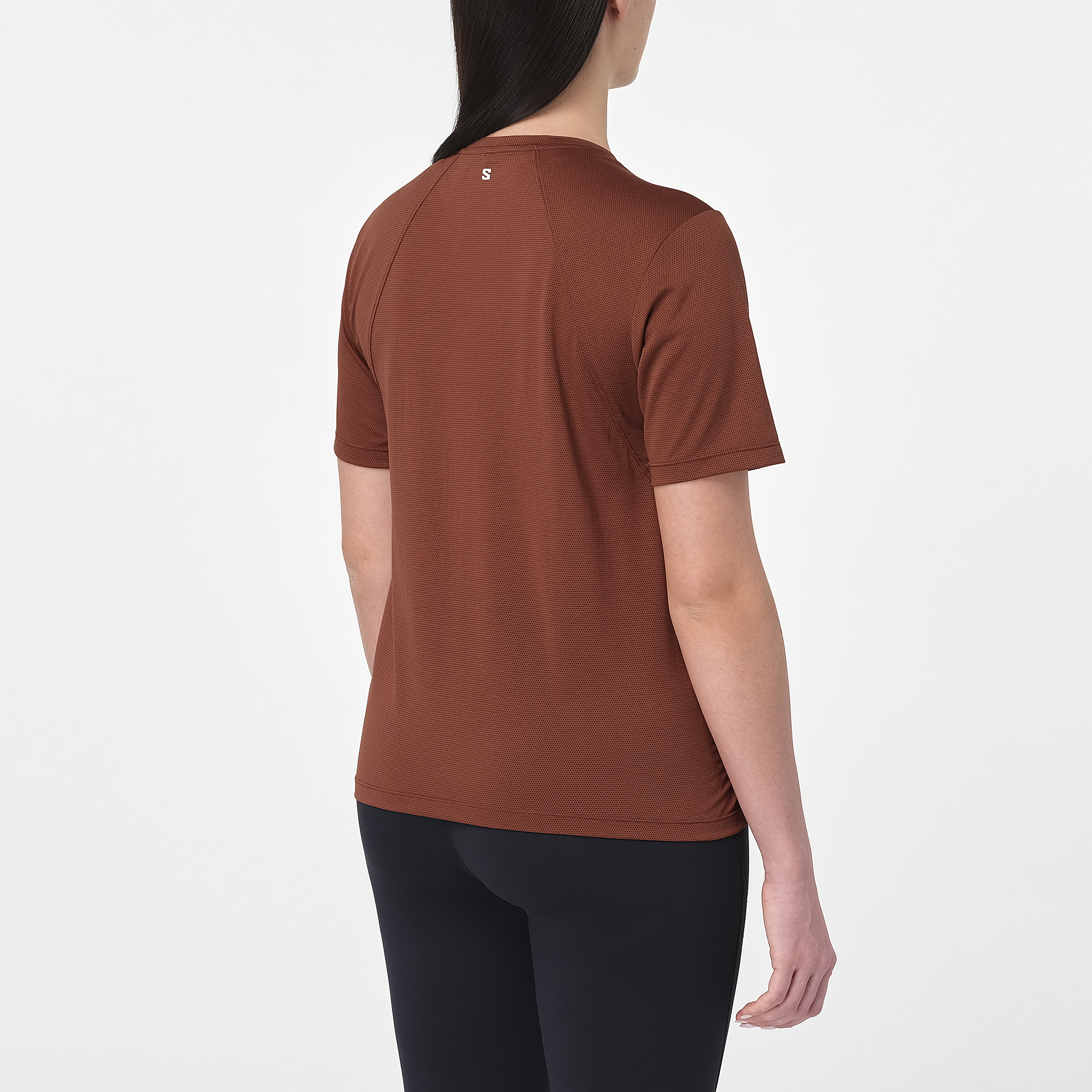 salomon shakeout core short sleeve running t-shirt for women, light and breathable run tee, dark burgundy colour with white salomon logo, back view of model wearing salomon tee on white background with black leggings 