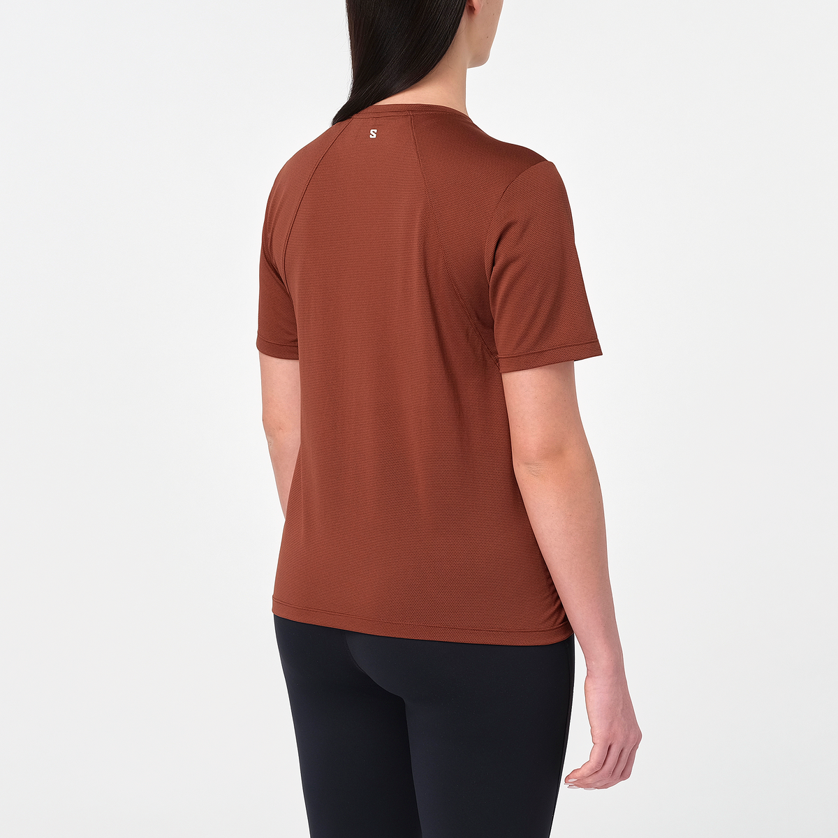 salomon shakeout core short sleeve running t-shirt for women, light and breathable run tee, dark burgundy colour with white salomon logo, back view of model wearing salomon tee on white background with black leggings 