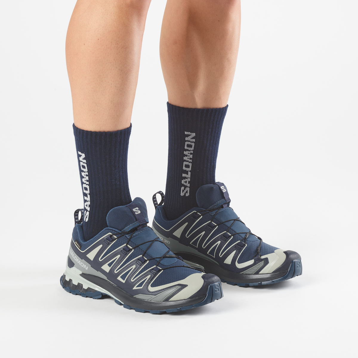 salomon xa pro 3d v9 gtx trail running and hiking shoe for men, waterproof salomon shoe, navy colour with light green details, close up of model wearing both shoes on a white background