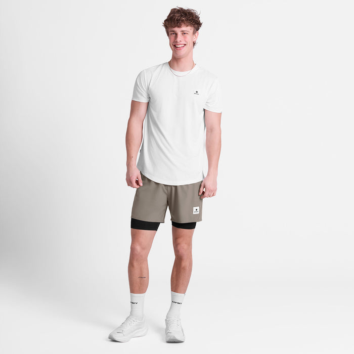 saysky pace 2-in-1 runnning short for men in taupe, comfortable running short with pockets, full body profile of man wearing saysky shorts and a white t-shirt