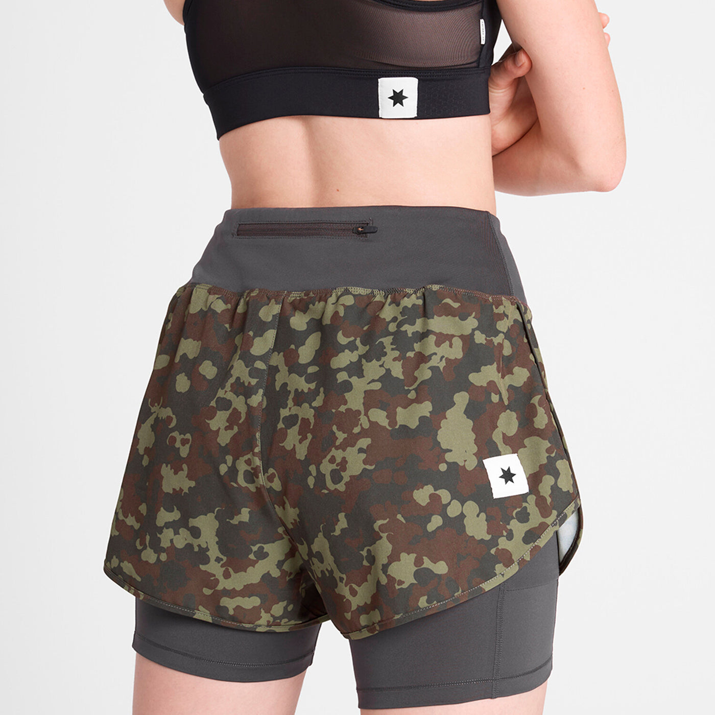 woman wearing saysky camo pace 2in1 run shorts for women showing back logo and zip pocket